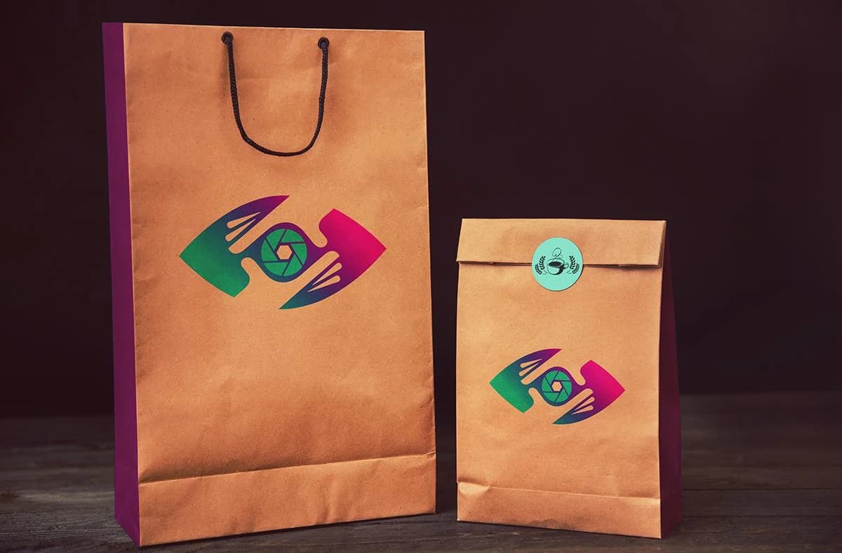 Two kraft coffee bags with the Capture That Media aperture logo on a dark backdrop