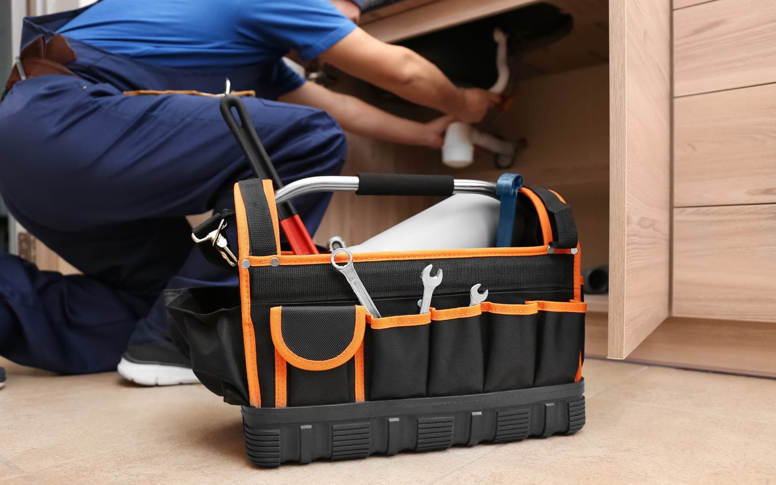 A plumber with tools repairing a sink in a San Antonio home