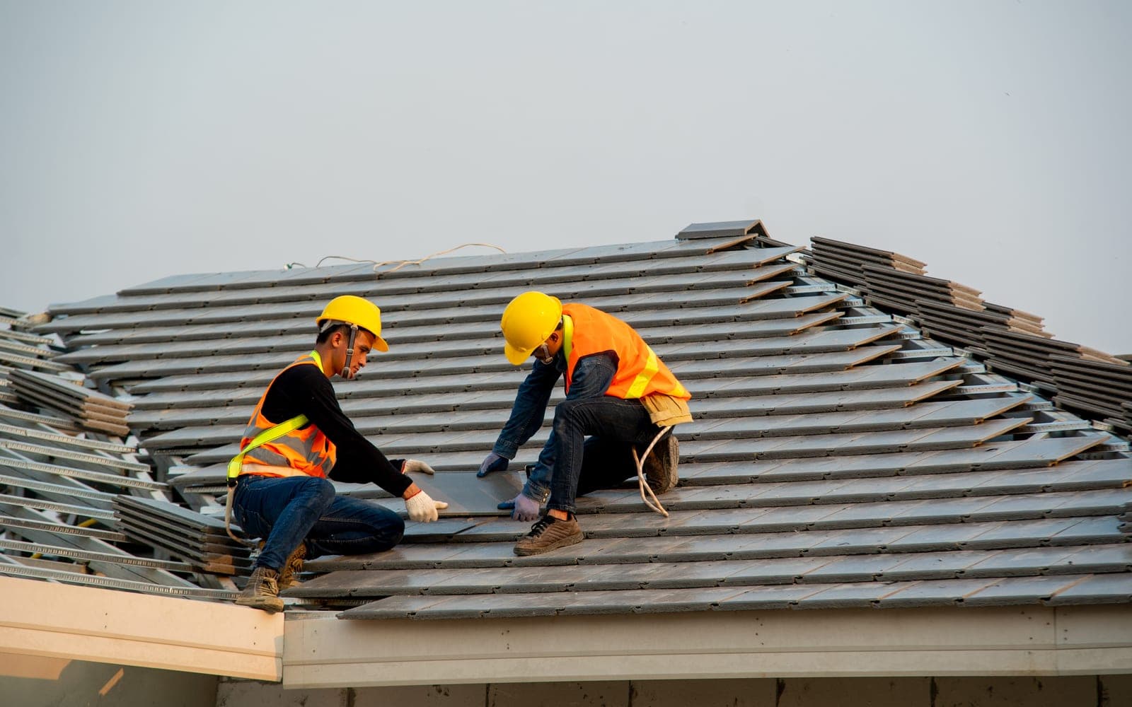 Two roofers installing a new tile roof on a residential home