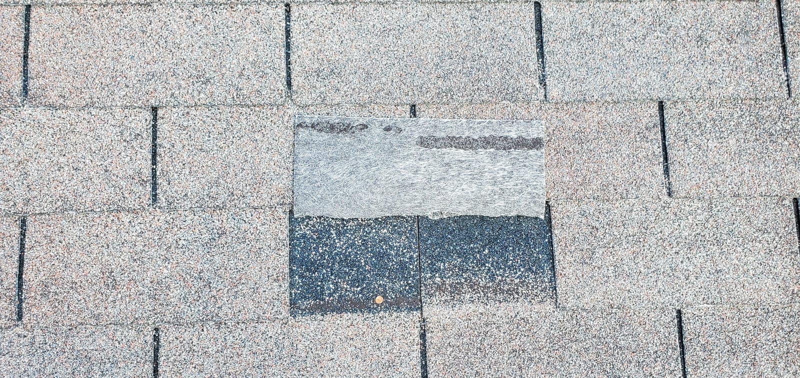 A roofer inspecting storm damage for an insurance claim