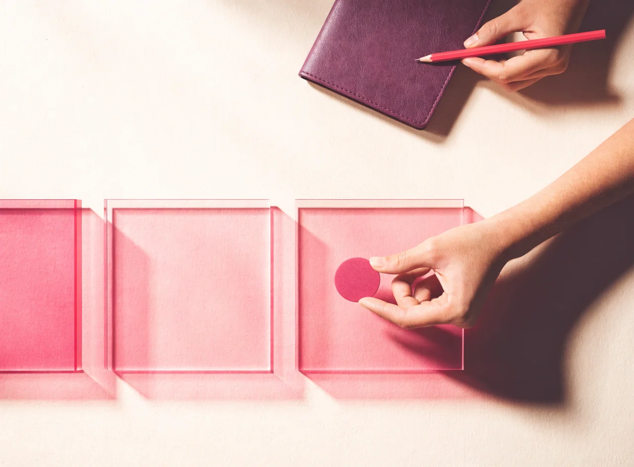 Illustrative overhead strategy workspace with blank acrylic panels, a notebook, and a round token.